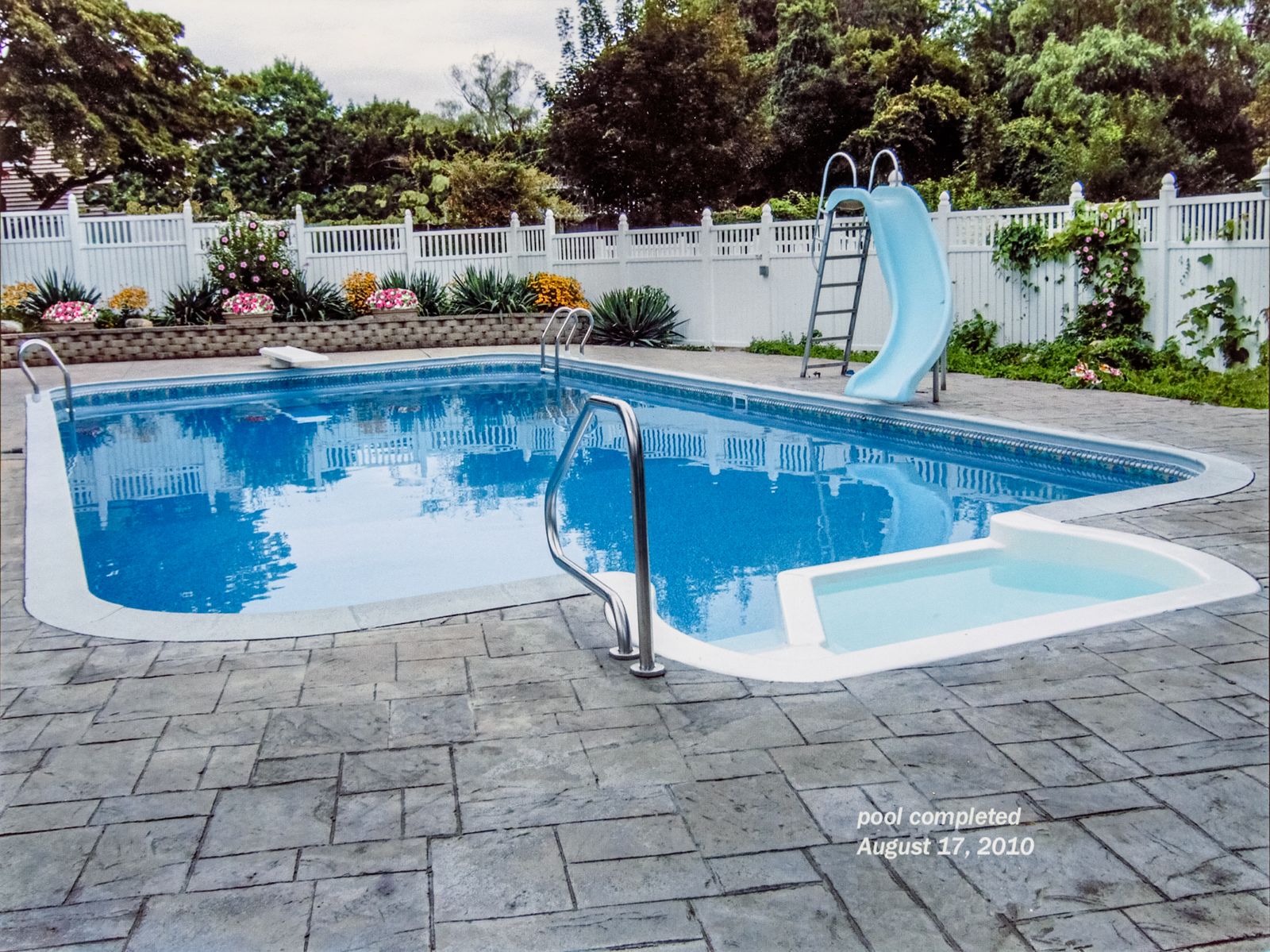 In-ground pool with slide, safety fence and pool house